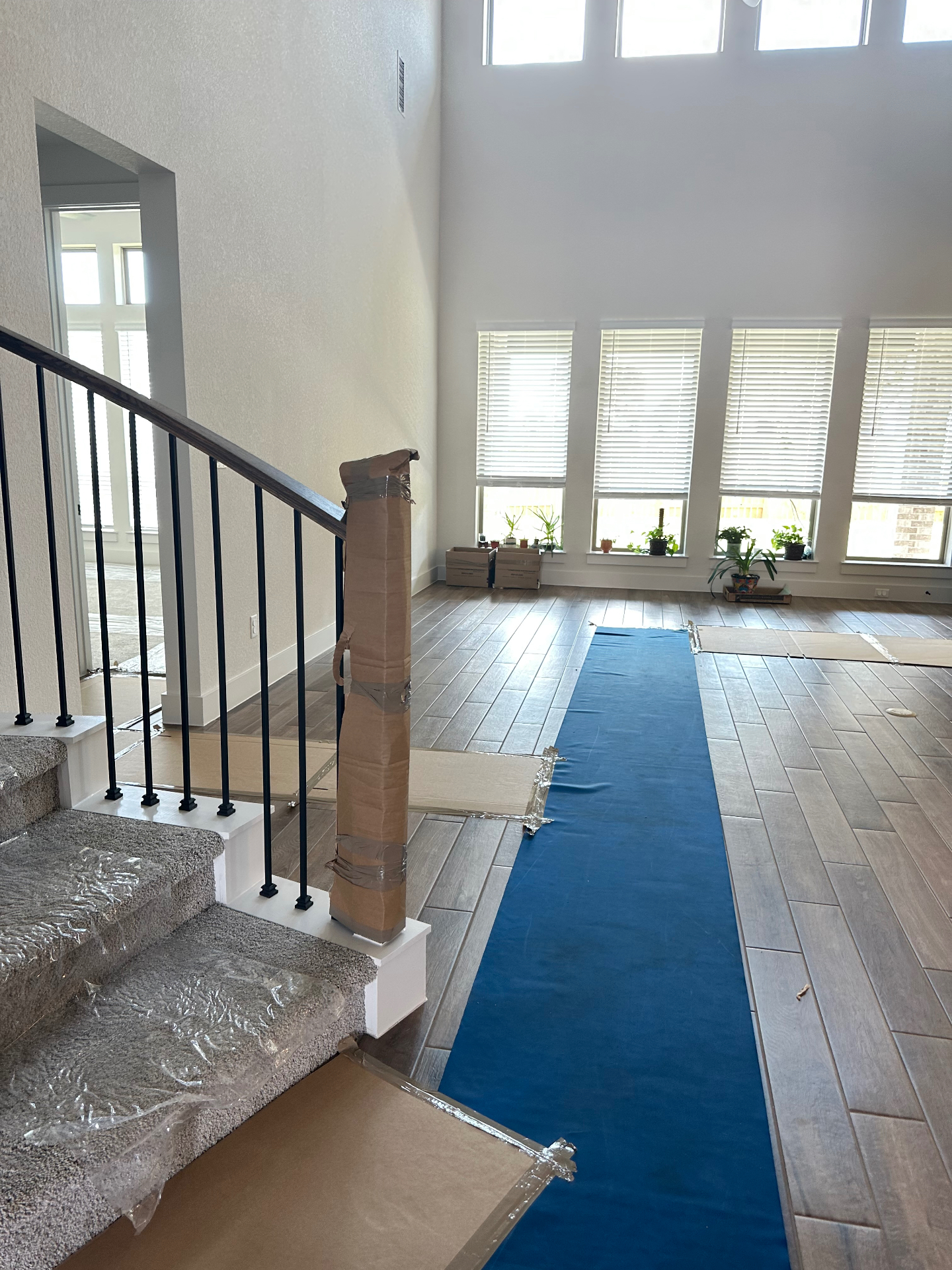 Blue neoprene floor runner laid down a hallway with padded banister and taped door jamb protection at a customer's Austin home