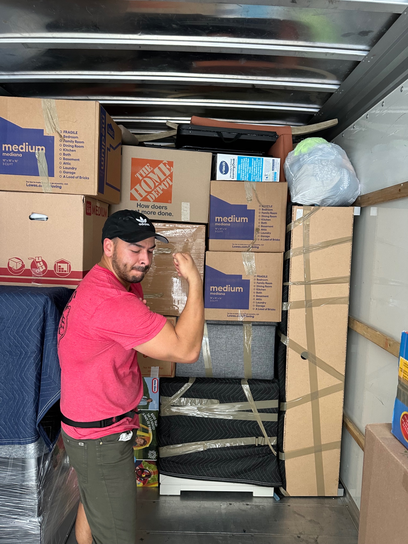 Mover securing labeled moving boxes tightly stacked inside a moving truck