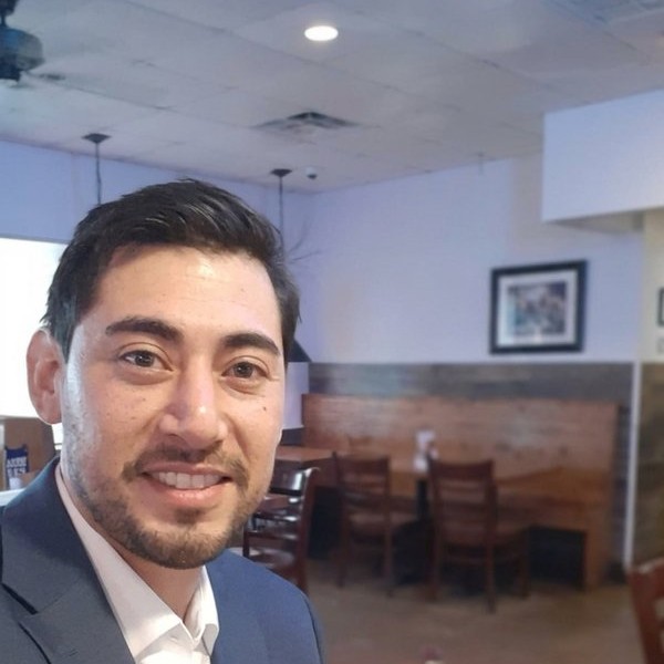 Bernie, co-owner of Lovable Movers, smiling in a grey suit — U.S. Marine Corps Iraq combat veteran